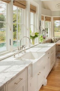 Natural rattan window shades complement an all-white kitchen
