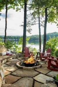 Red Adirondack chairs and a stone bench surround the perfect fire pit