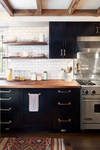 White subway tile backsplash pops against dark kitchen cabinets and butcher block counters