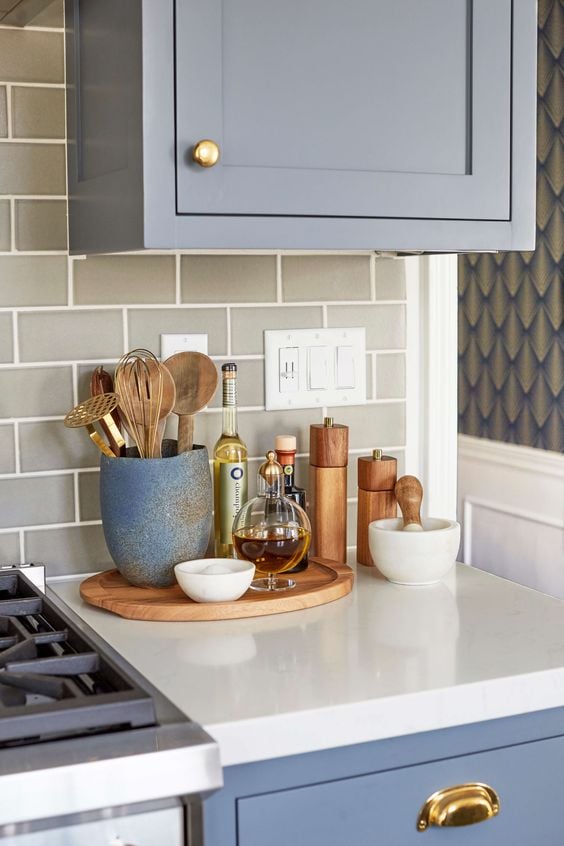 A wood kitchen tray collects olive oil, spices, and cooking utensils to clear up countertop space - Source 