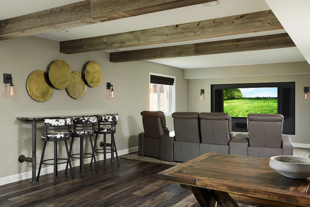 A drink ledge sits behind this basement’s theater seating, offering ample space for guests to mingle or pull up a seat to tune in to the show.