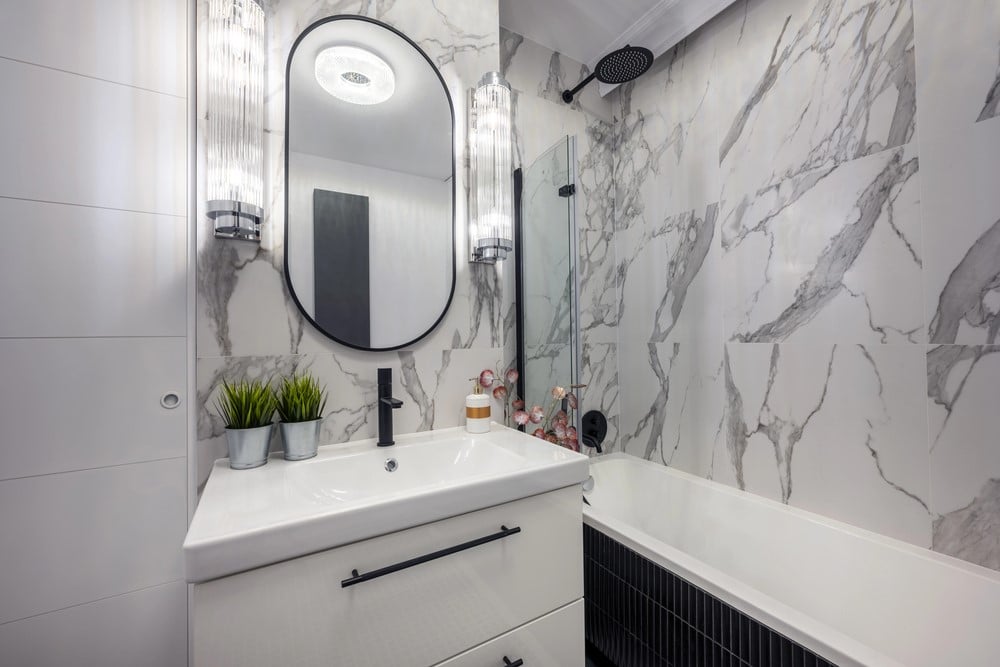 Carrying the marble look shower wall tile to the vanity backsplash creates a seamless cohesive look in this small bathroom.
