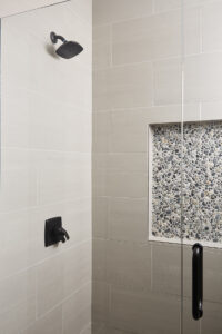 With a little personality added via the pebble tile shower niche, this bathroom gets a dose of style that wows. (Interior Design by Carla Bast | Carla Bast Design)