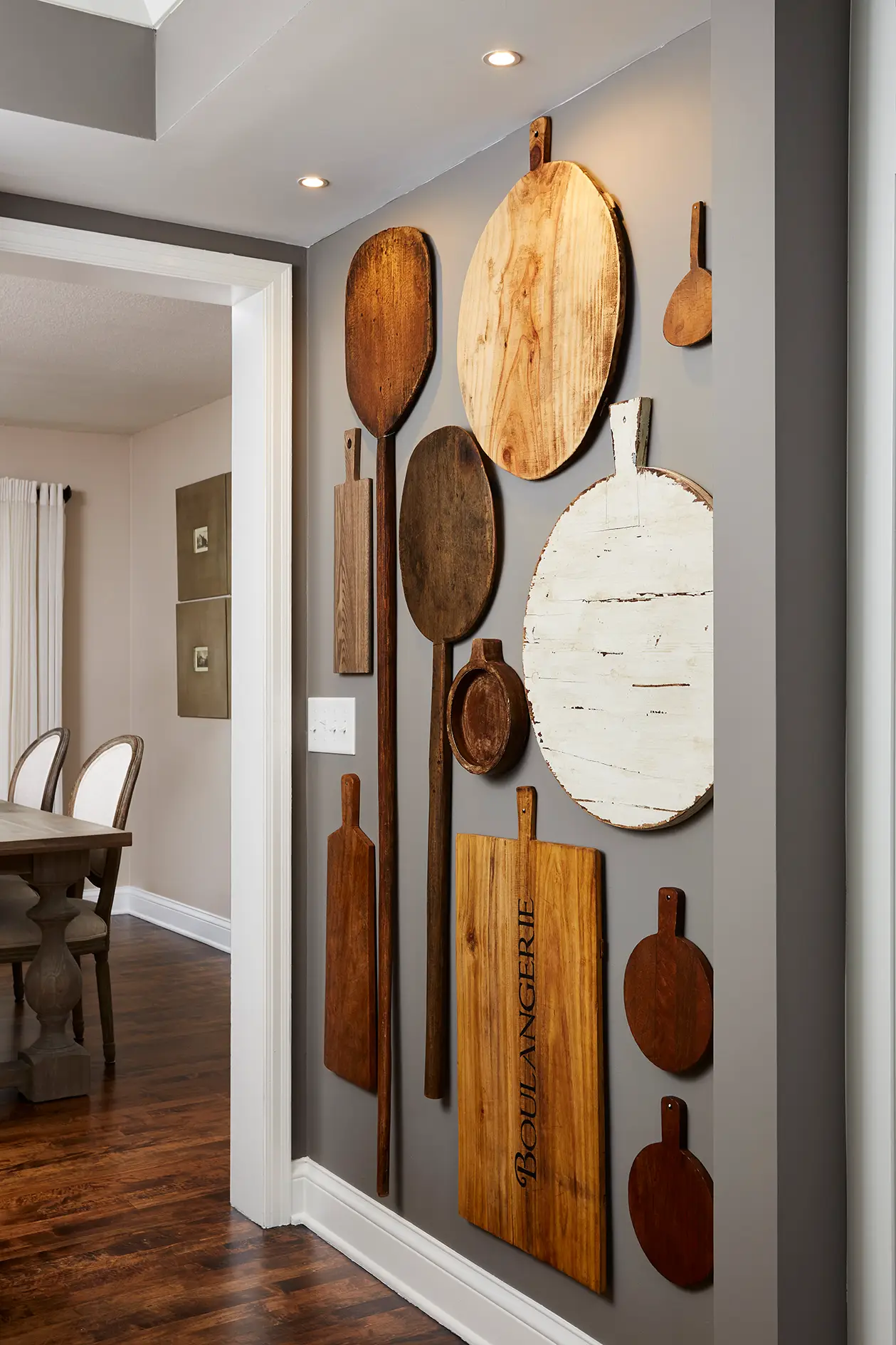 An entire wall of vintage wood kitchen boards hung in a vertical pattern from floor to ceiling elevates this hallway to the dining space. 