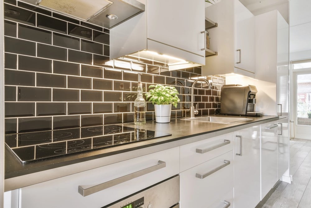 glossy black subway tile with white grout in a white kitchen