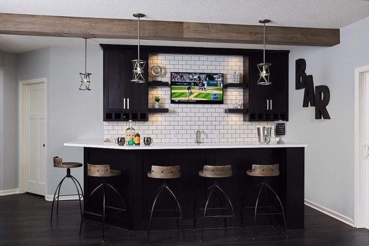 Final result of the basement bar remodel in Chaska. The final design includes white tile backsplash, a dark kitchen island with a white countertop, and stylish bar stools.