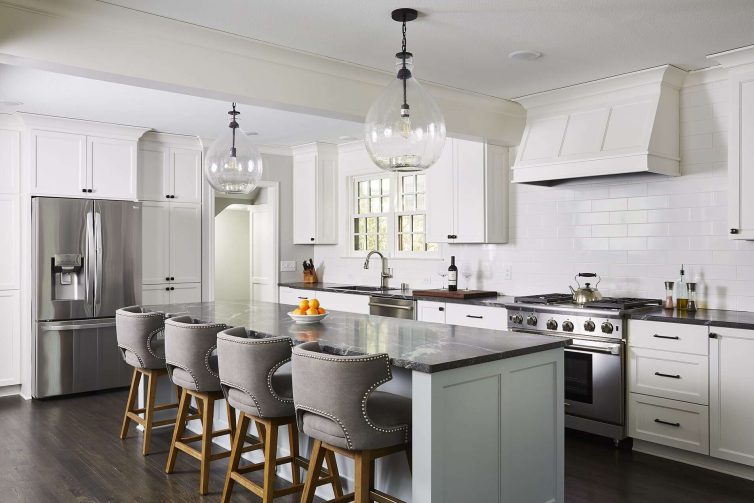white kitchen with grey island, black granite and subway tile